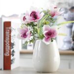 Cette image montre une fausse fleur rose. Cette fleur artificielle est une orchidée. Cette fausse fleur est dans un vase